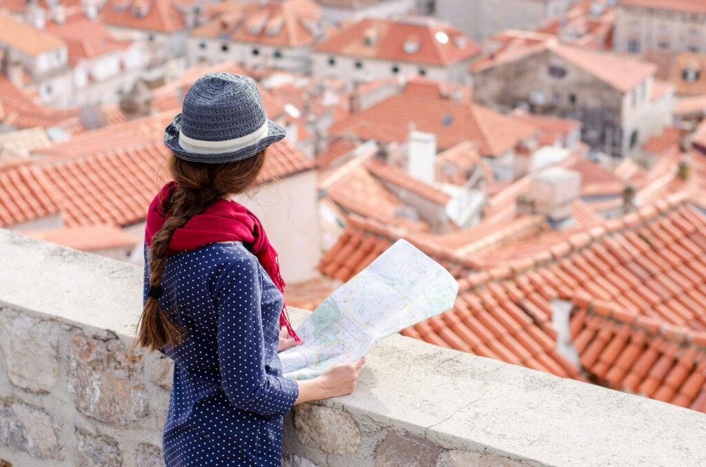 Dubrovnik traveler. Young woman with a town map searching for right direction. Hat. Europe travel.
