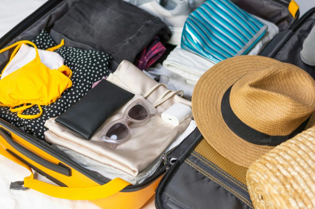 Flat lay composition with packed suitcase and travel accessories