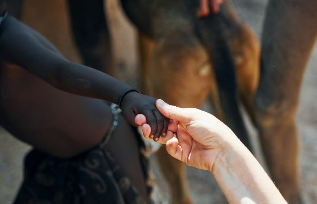 Touching hands, greetings gesture. Tourists is in Namibia with African kids